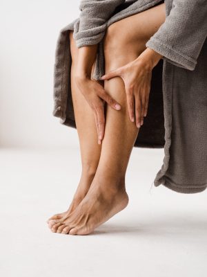 African american girl touching her legs and looking at veins. Deep vein thrombosis and varicose of woman. Sclerotherapy procedure at visiting vascular surgeon doctor